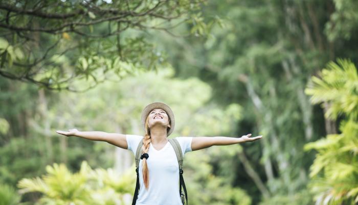 young-happy-woman-with-backpack-raising-hand-enjoy-with-nature