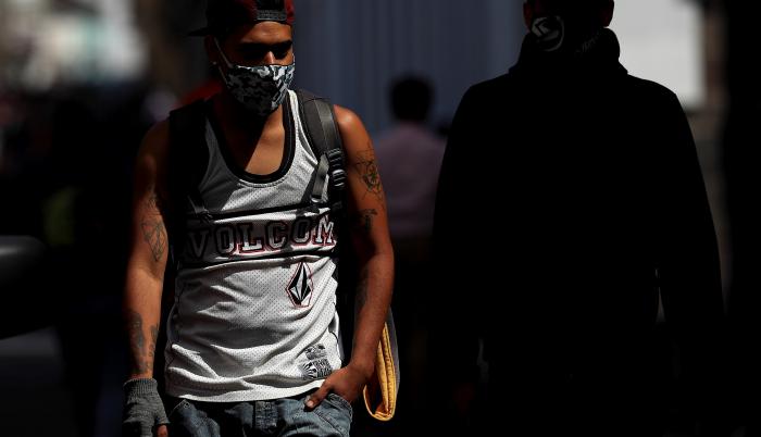 En la imagen, un hombre con mascarilla camina por una calle de Quito (Ecuador).