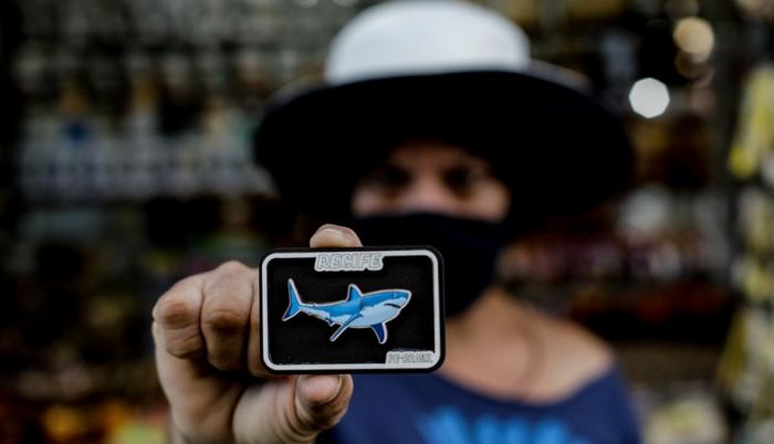 Una turista muestra un imán con la imagen de un tiburón, el 12 de agosto de 2021, en Jaboatao dos Guararapes (Brasil).