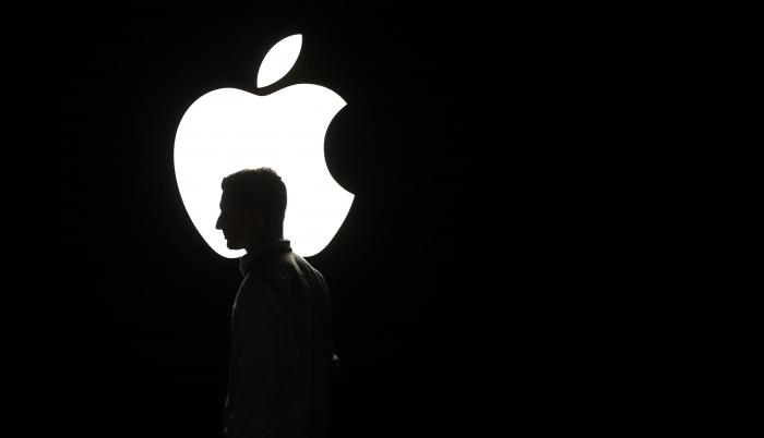 La silueta de un hombre se ve frente al logo de Apple, en una fotografía de archivo.