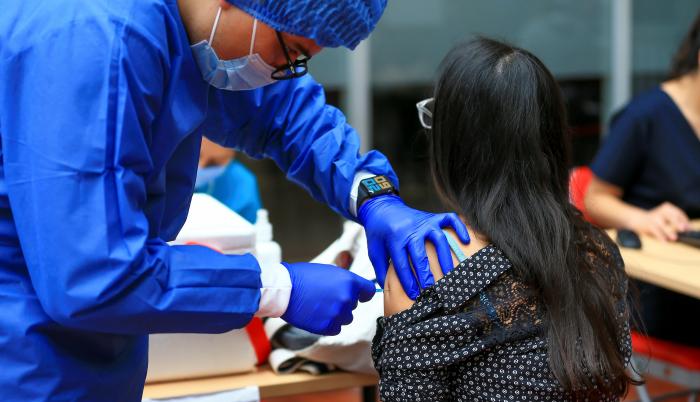 Fotografía de archivo en la que se registró a una mujer al ser vacunada contra la covid-19, en la Universidad de Las Américas, en Quito (Ecuador).