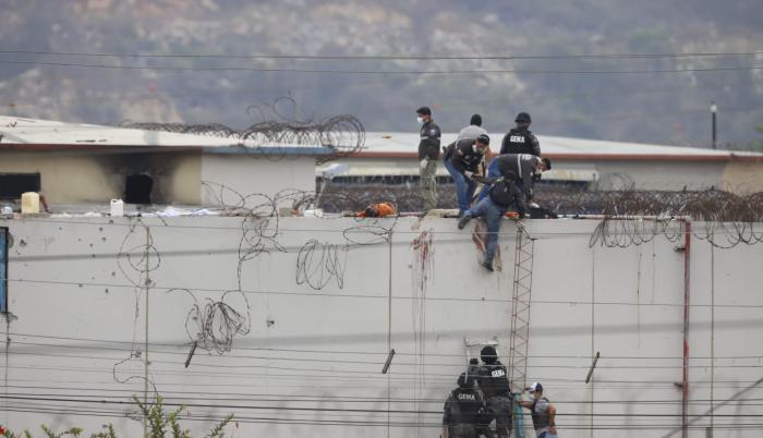 Sobre un muro del pabellón 2 se observa cómo se realizan pericias alrededor de un cadáver.