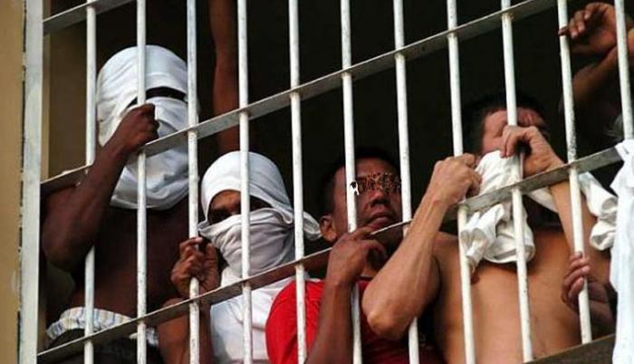 Un grupo de personas privadas de la libertad, tras las rejas.