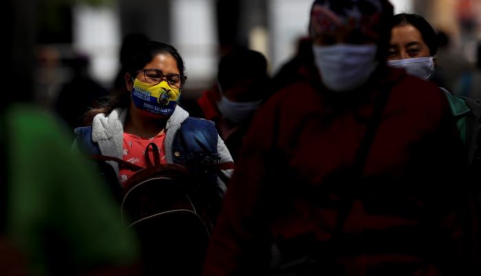 Personas con mascarilla caminan por una calle en la ciudad de Quito