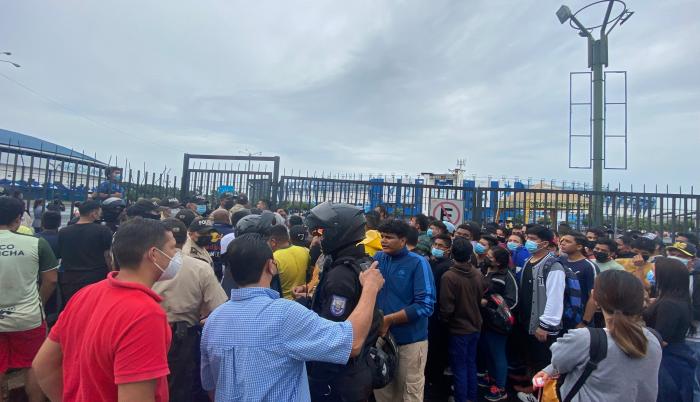 Los aficionados pugnan por ingresar a la explanada del estadio Modelo Alberto Spencer Herrera para comprar un boleto, mientras la policía intenta preservar el orden.