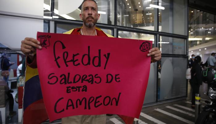 Un aficionado sostiene un cartel de apoyo al exfutbolista colombiano Freddy Rincón, quien sufrió un grave accidente de tráfico en la madrugada de este lunes, hoy, a las afueras de la clínica Imbanaco donde se encuentra hospitalizado, en Cali (Colombia).