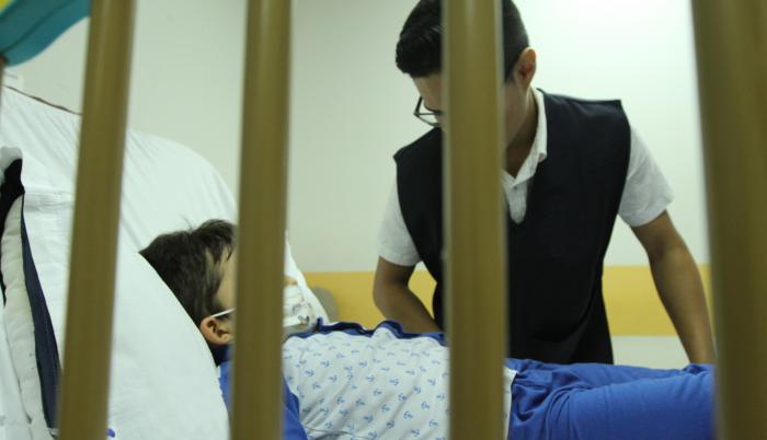 Atención. Un niño se recupera de un tratamiento hospitalario, mientras recibe la visita de un conocido.