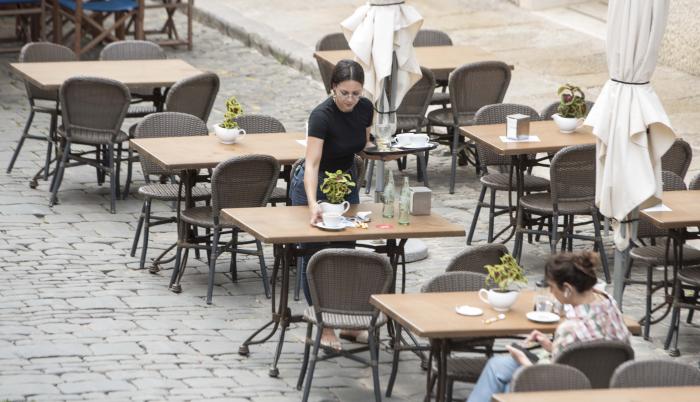 Imagen de archivo de una trabajadora recoge una mesa de una terraza en un bar.