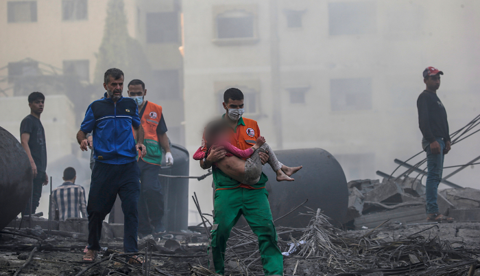 Gaza. Un palestino carga a una niña herida que ha sido recuperada de entre los escombros.