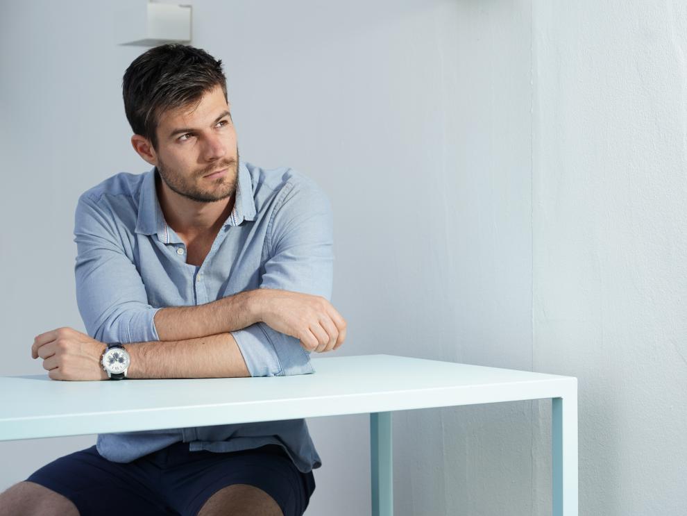 young-hispanic-male-wearing-blue-shirt-posing-white-desk