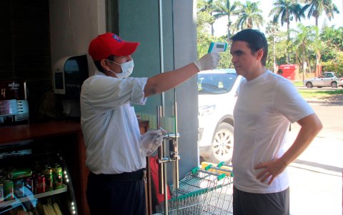 Un empleado toma la temperatura a un hombre en la entrada a una tienda durante el primer día de cuarentena (22 de marzo) debido a la crisis por el coronavirus en Santa Cruz (Bolivia).