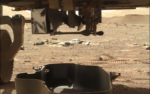Una foto de un folleto facilitada por la NASA muestra una imagen del Helicóptero Ingenuity de la NASA (arriba) aún conectado al rover Perseverance Mars de la NASA después de que se desprendiera el escudo de escombros (abajo) que lo protegía.