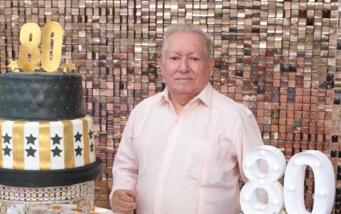 El cumpleañero posa junto a la torta.