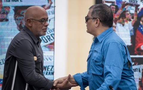 El presidente de la Asamblea Nacional, Jorge Rodriguez (i) y el expresidente de Ecuador, Rafael Correa, se saludan en un acto por el