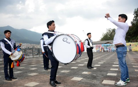 La banda de paz, que cuenta con cachiporreros, acompaña a las jóvenes.