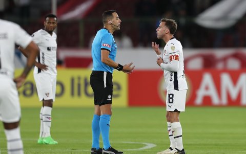 Lucas Piovi de LDU discute con el árbitro Esteban Ostojich .