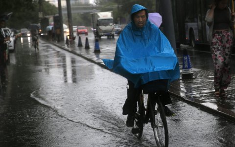 Un ciclista circula bajo un chaparrón en Pekín, China,