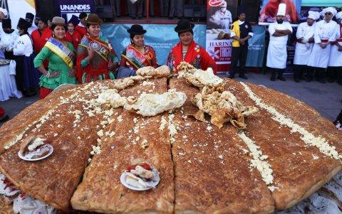 Mujer aimara posan junto al Sándwich de chola más grande del mundo, este martes en La Paz (Bolivia).