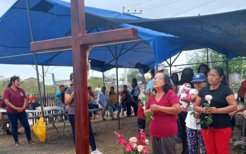 Fieles católicos se suman a las oraciones ante la cruz.