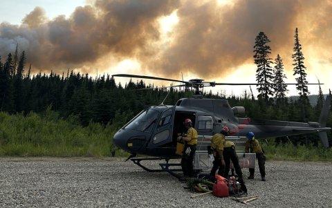 Un grupo de bomberos toma un descanso a un costado de uno de los helicópteros con los que se monitorea el avance del fuego.