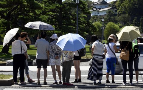 Un grupo de personas trata de protegerse del sol en una mañana de mucho sol en la capital japonesa.