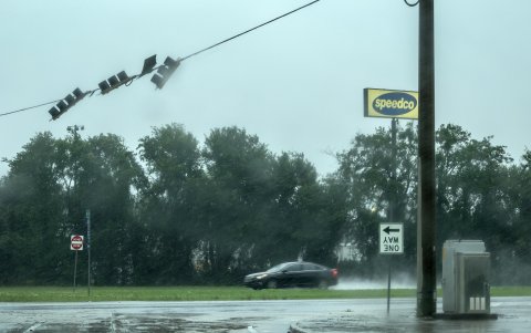 Un automóvil pasa bajo señales de tráfico meciéndose con el viento debido a la tormenta tropical Debby en Waverly, Georgia, EE. UU., 5 de agosto de 2024.