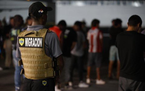 Un agente de migración de Panamá vigila a ciudadanos colombianos antes de ser deportados a su país.