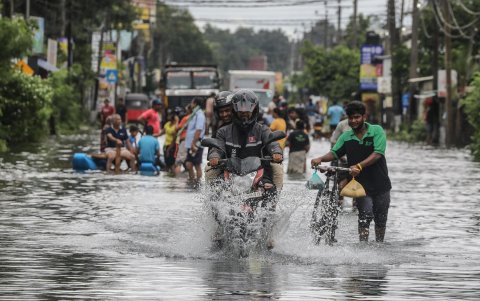 Víctimas de las inundaciones de Sri Lanka caminan por una carretera inundada después de fuertes lluvias en el suburbio de Colombo, Sri Lanka, este lunes.
