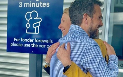 El director ejecutivo del aeropuerto de Dunedin, Daniel De Bono, y la directora de desarrollo comercial, Megan Crawford, abrazados junto el cartel que indica 