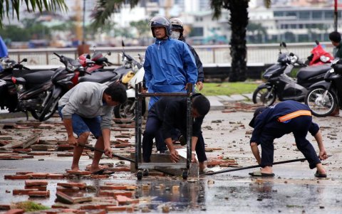 Un grupo de vietnamitas trata de arreglar los daños causados por la tormenta Trami tras tocar tierra el domingo en el centro de Vietnam.