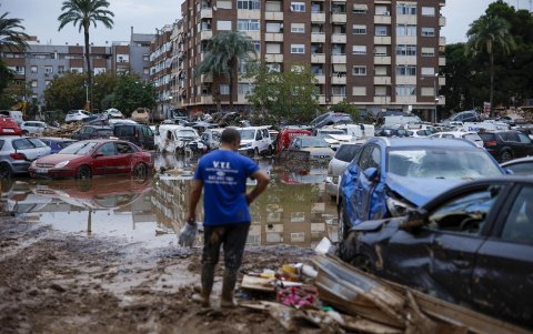 Un hombre junto a varios coches, arrastrados por el agua tras el paso de la dana, en Paiporta este viernes.