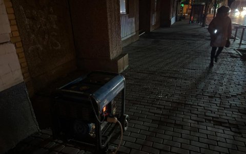 Una mujer camina con una linterna cerca a un generador de energía durante un apagón parcial en Kiev el 28 de noviembre de 2024, tras los ataques rusos a la infraestructura energética ucraniana.