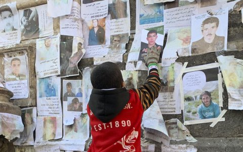 Un niño coloca una foto de un familiar aún en paradero desconocido un mes después del derrocamiento del régimen sirio, este 7 de enero de 2025 en Damasco.