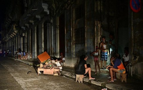 Los cubanos conversan por la noche en una calle durante un apagón nacional causado por una falla de la red eléctrica en La Habana el 18 de octubre de 2024.