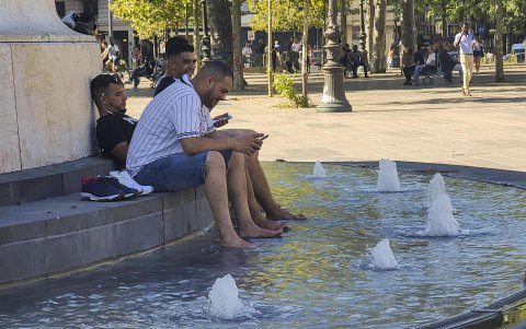 Varias personas se remojan en una fuente ornamental de la plaza de la República de París (Francia)