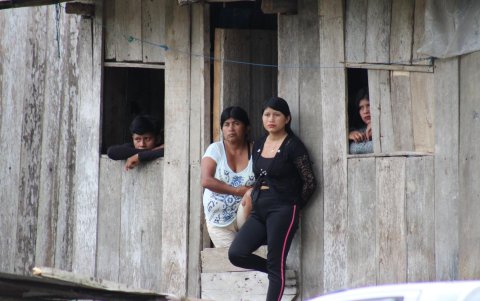 Una familia de la comunidad Naranjal de los Chachis ve pasar el tiempo en el portal de su casa de madera.
