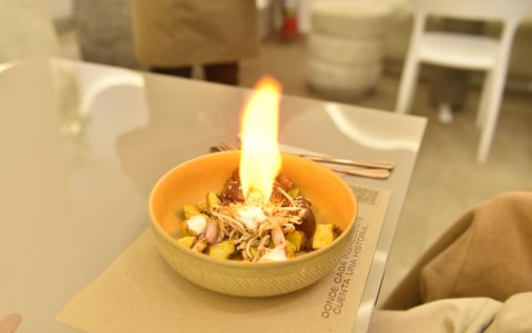 El fuego es el tercer tiempo del menú. El plato combina panceta de cerdo, papas, brotes de soya y salsas, acompañado de una breve intervención con llamas frente a los comensales.