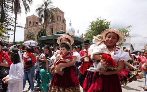 Vestimentas. Dos jóvenes vestidas de chola cuencana llevan la imagen del Niño y una mascosta.