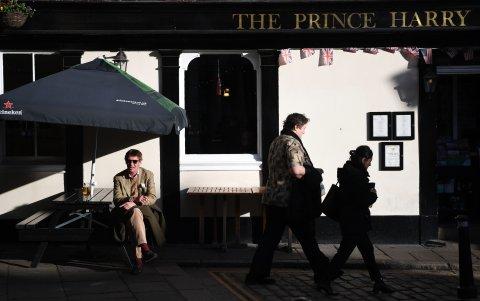 Un hombre se sienta fuera de un bar que lleva el nombre de Harry.