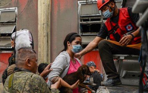 Los socorristas ayudan a una residente y a su perro a subir a un camión durante la evacuación en la ciudad de Talisay.