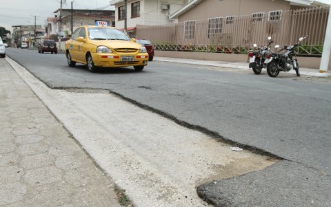 Los carros sortean los baches del pavimento.