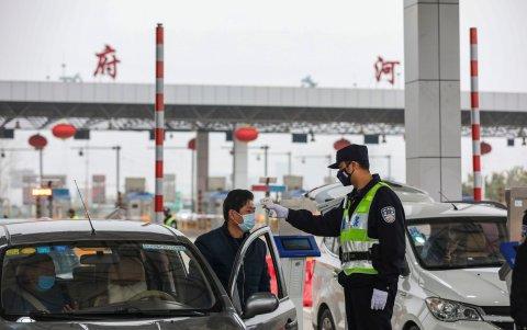 WUHAN. Un policía toma la temperatura a un conductor en una de las avenidas principales de esta ciudad de China.