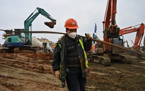 Un trabajador lleva materiales en el sitio de construcción de un nuevo hospital que se construye en  Wuhan en la provincia central de Hubei de China.