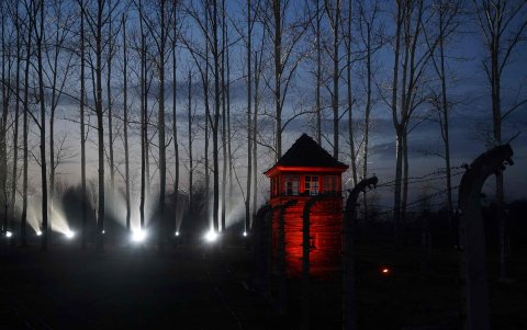 Una imagen tomada este 27 de enero muestra una torre de vigilancia iluminada cerca del alambre de púas que encierra el sitio conmemorativo del antiguo campo de exterminio nazi alemán Auschwitz.