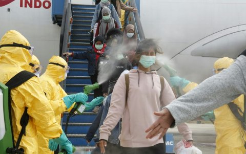 Un equipo desinfecta a los estudiantes indonesios que desembarcan en el aeropuerto internacional Hang Nadim en Batam, luego de su evacuación de Wuhan.
