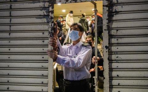 Un guardia de seguridad cierra el frente de un edificio después de que se agotaron las existencias de máscaras faciales, miles de personas hicieron cola durante horas para comprarlas.)