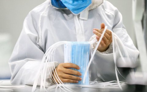 Un trabajador produce máscaras faciales protectoras en una fábrica en Qingdao, en la provincia oriental china de Shandong,