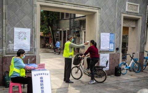 GUANGZHOU. Un mujer intenta ingresar a un barrio cerrado en esta ciudad. Los controles son intensos en estos días en toda China.