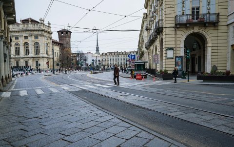 TURÍN. Una persona camina por el paso de cebra en la plaza Castello, con una ausencia absoluta de tránsito peatonal y de vehículos.