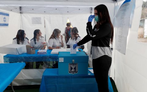 Una trabajadora de la Junta Electoral Cetral israelí realiza una demostración del funcionamiento de una cabina de voto preparada para personas en cuarentena por el Coronavirus en Tel Aviv.